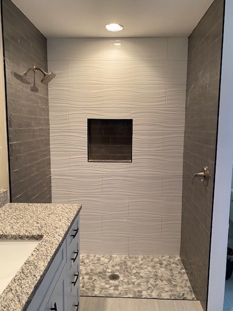 Shower with textured accent wall and pebble floor