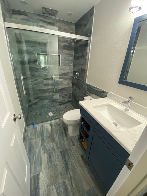 Bathroom with blue vanity and glass shower